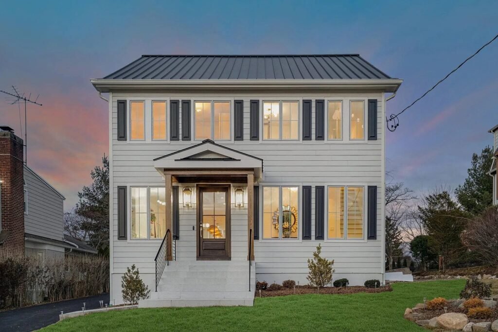 Newly built white colonial home lit at twilight in Westchester County