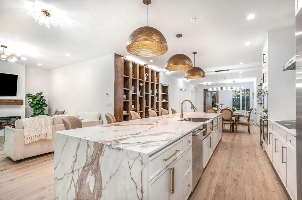 Kitchen with a calacatta marble waterfall island and brass pendants