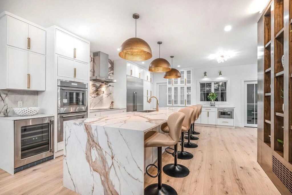 Marble island with brass stools and open shelving beyond