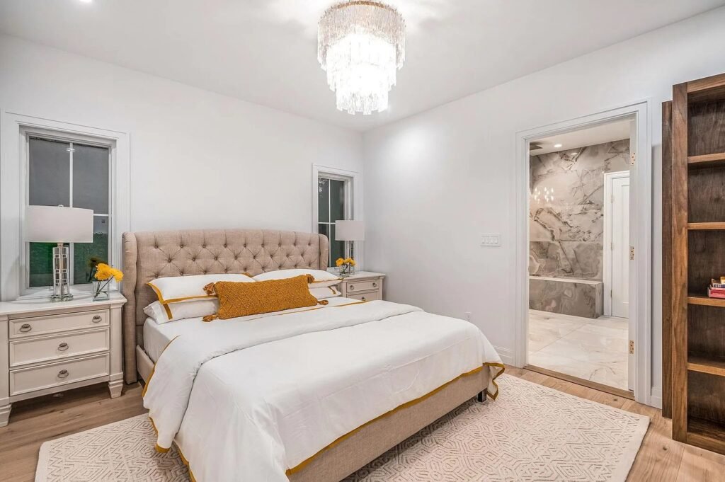 Primary bedroom with an upholstered headboard and ensuite beyond