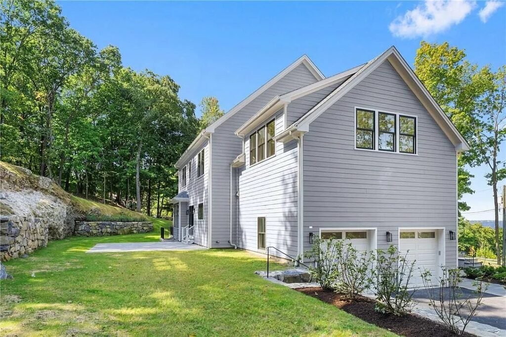 New construction home set among mature trees and a rock outcrop