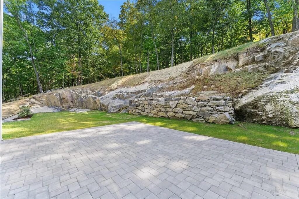 Paver driveway curving past an exposed rock outcrop