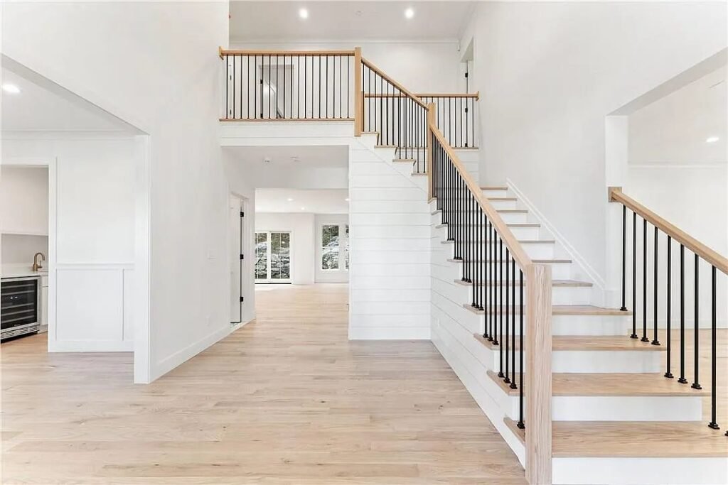 Open stair with white risers and a black metal railing