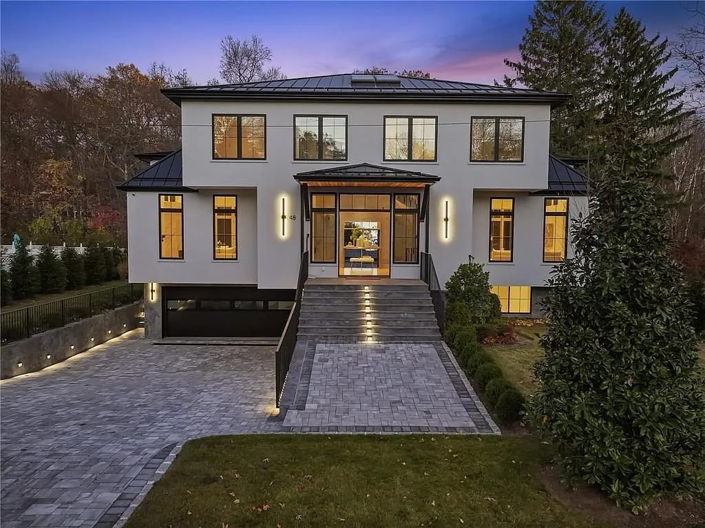 Contemporary new-construction home at dusk with illuminated entry