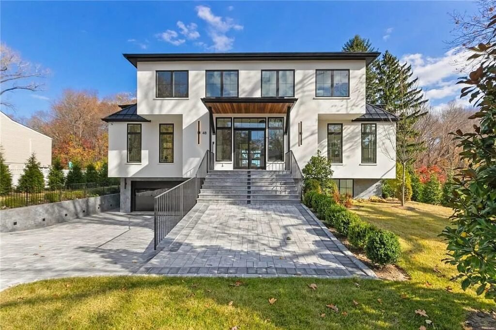 Daytime front elevation showing the contemporary massing and stone entry path