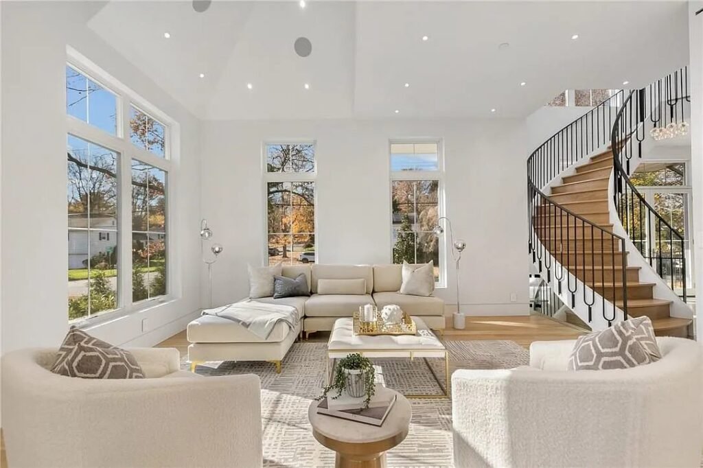 Double-height living room with a curved staircase and floor-to-ceiling glass