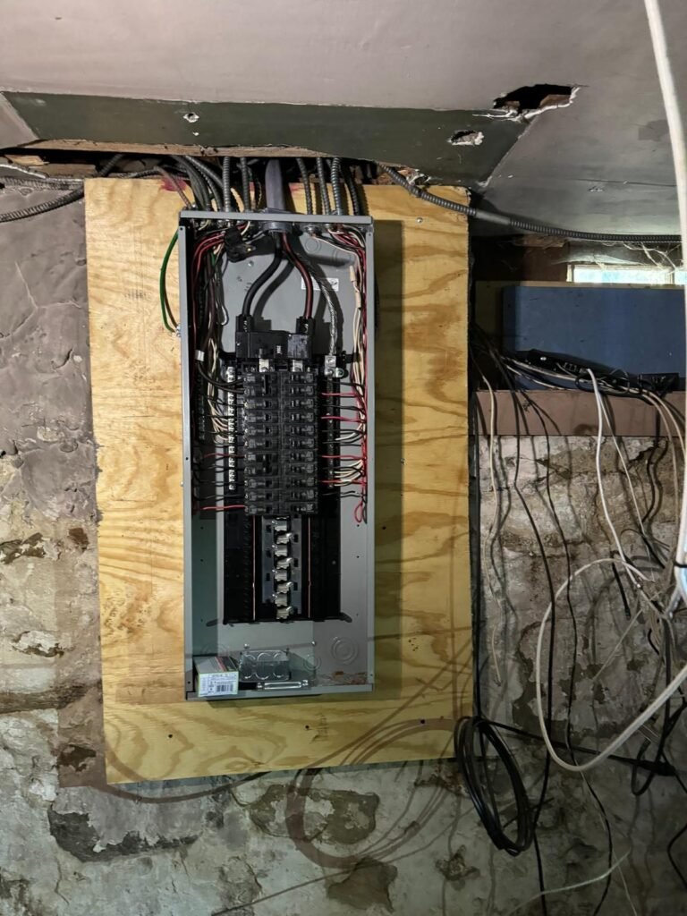 Electrician working inside an open residential electrical panel during a service upgrade